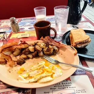 Eggs and meat traditional Over medium home fries seasoned on the grill bacon sourdough toast coffee
