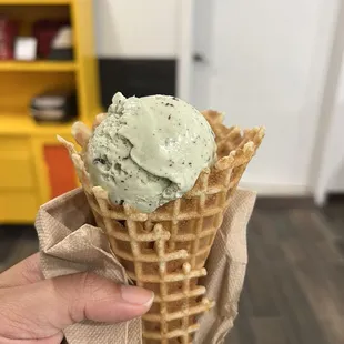 Half a scoop of mint chocolate chip in a waffle cone