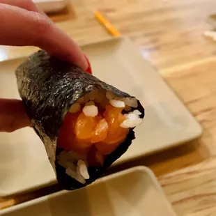 a hand holding a piece of sushi