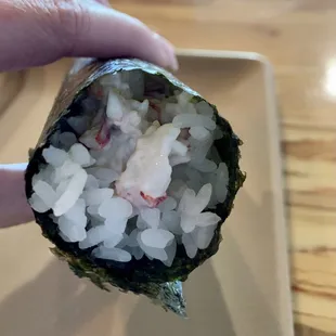 a hand holding a piece of sushi