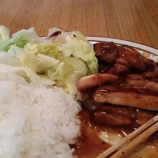 a plate of food with rice and chopsticks