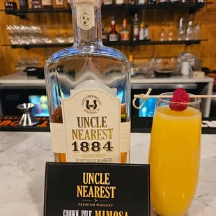 a bottle of uncle nearest next to a glass of orange juice