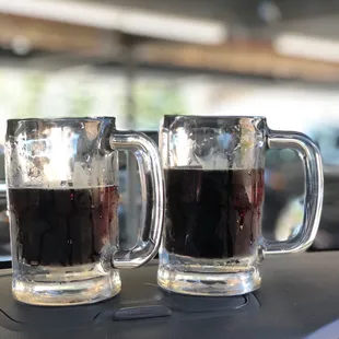 two mugs of coffee on the dashboard of a car
