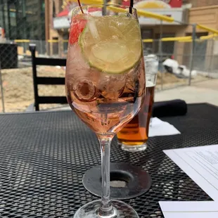 a glass of rose wine with a slice of lime