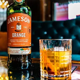 a bottle of jameson orange next to a glass of whiskey