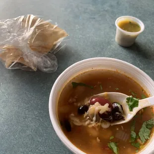 Sopa de frijoles con queso, tortillas, salsa verde picante