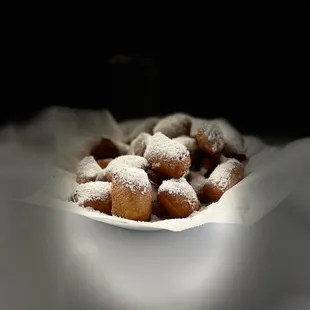 a bowl of powdered sugared doughnuts