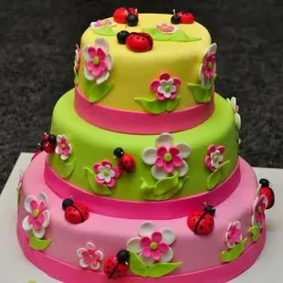 a three tiered cake with ladybugs and flowers