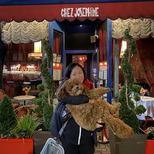 a woman holding a dog in front of a restaurant