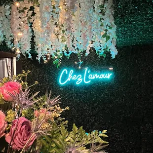 a neon sign with flowers and greenery