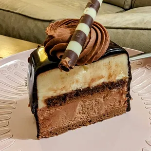 Triple chocolate dessert. Chocolate mousse with thin layers of cake is encased in a shiny chocolate ganache glaze.