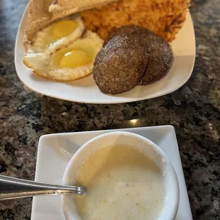 Breakfast platter with sausage, eggs, toast, grits, and hashbrowns.