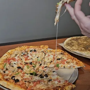a person taking a slice of pizza