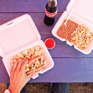 a man eating a hot dog, beans, and macaroni and cheese