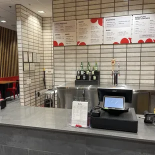 a restaurant counter with a menu on the wall