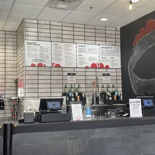 a restaurant counter with menus on the wall
