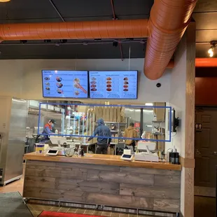 a restaurant counter with a menu on the wall