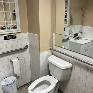 a bathroom with a toilet, sink, and mirror