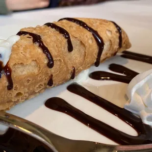 a crepe with whipped cream and chocolate sauce