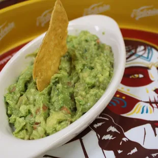 a bowl of guacamole with a tortilla chip in it