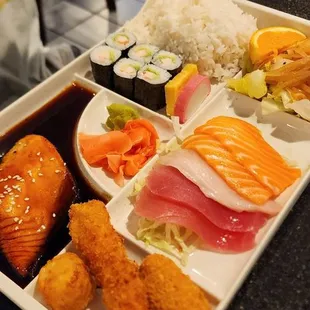 a man taking a picture of a tray of sushi