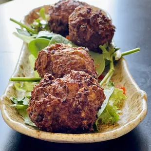 three meatballs on a plate with lettuce