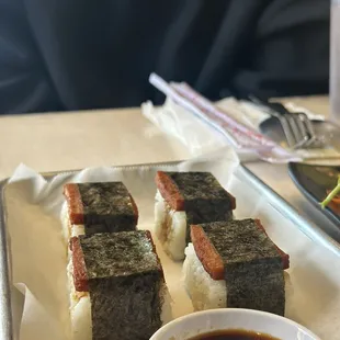 a plate of sushi and a bowl of sauce
