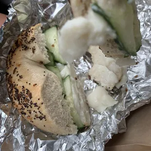 a hand holding a bagel sandwich