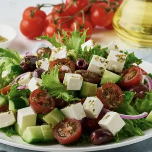 a salad with tomatoes, cucumbers, olives, and feta cheese