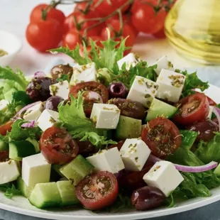 a salad with tomatoes, cucumbers, olives, and feta cheese