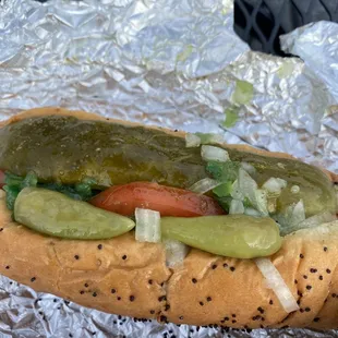 a hot dog with pickles and tomatoes