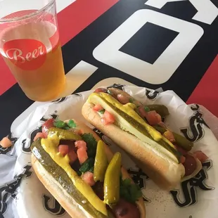 a glass of beer and a plate of hot dogs