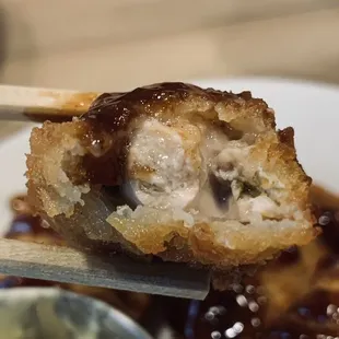 a close up of a fried sushi on a plate with chopsticks