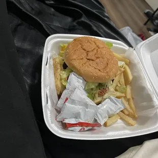 a hamburger and fries in a styrofoam container