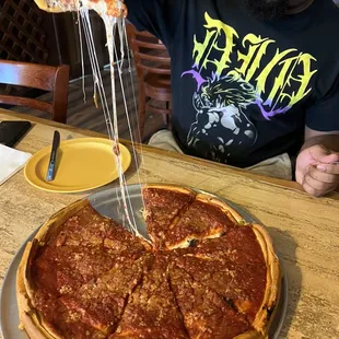  man holding a slice of deep dish pizza