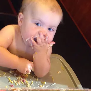 a baby sitting in a high chair eating cake