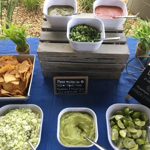 This is a view of our topping bar which includes: fresh guacamole, cabbage, chips, salsas, onion/cilantro, limes and a chalkboard menu.