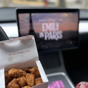 ows a person holding a box of chicken nuggies