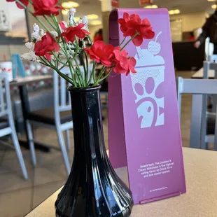 ows a black vase with red flowers