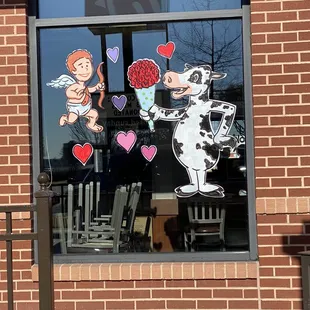 ows a cow and a dog with hearts in the window