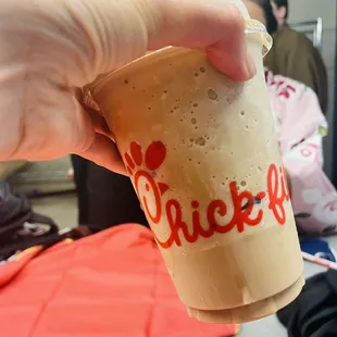 ows a hand holding a cup of coffee