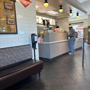 ows a man standing at the counter of a fast food restaurant