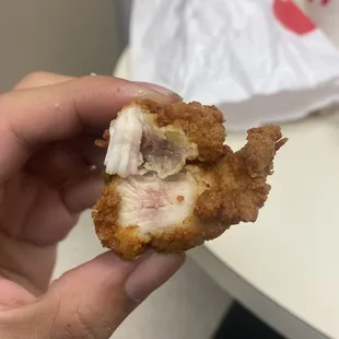 ows a hand holding a piece of chicken