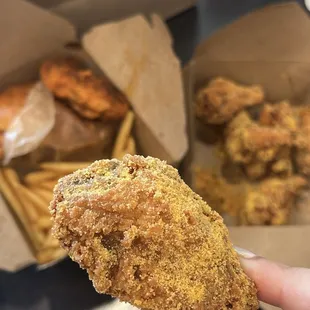 a hand holding a piece of fried chicken
