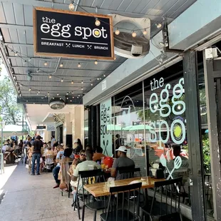 people sitting at tables outside a restaurant