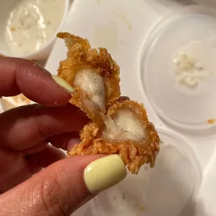 a hand holding a piece of fried chicken