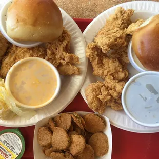 two plates of fried chicken, a roll, and a side of coleslaw