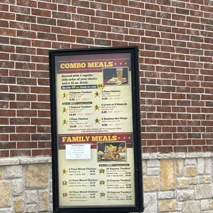 a menu on a sign in front of a brick building