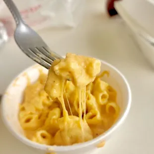 a fork lifting up a bowl of macaroni and cheese