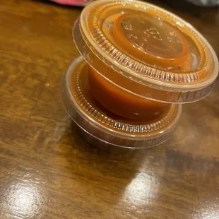 two plastic containers of food on a wooden table